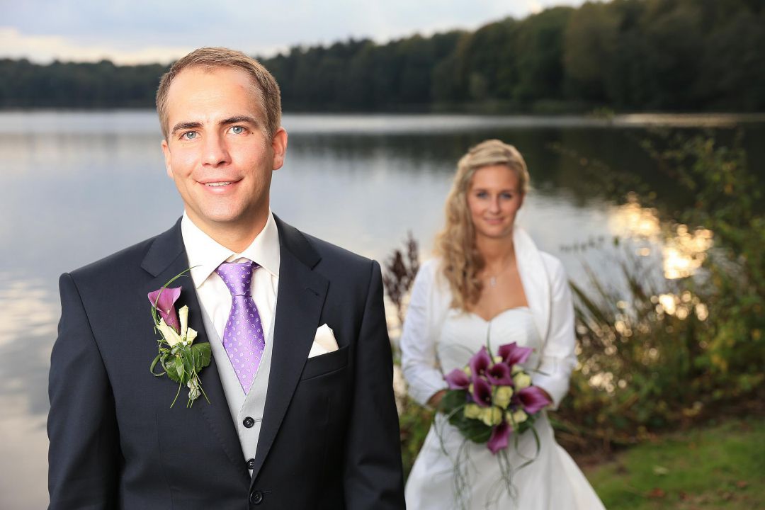 Bild vom Brautpaar vor einem See mit strahlendem Bräutigam, Hochzeitsfotos von Peter Vogel, Hamburg