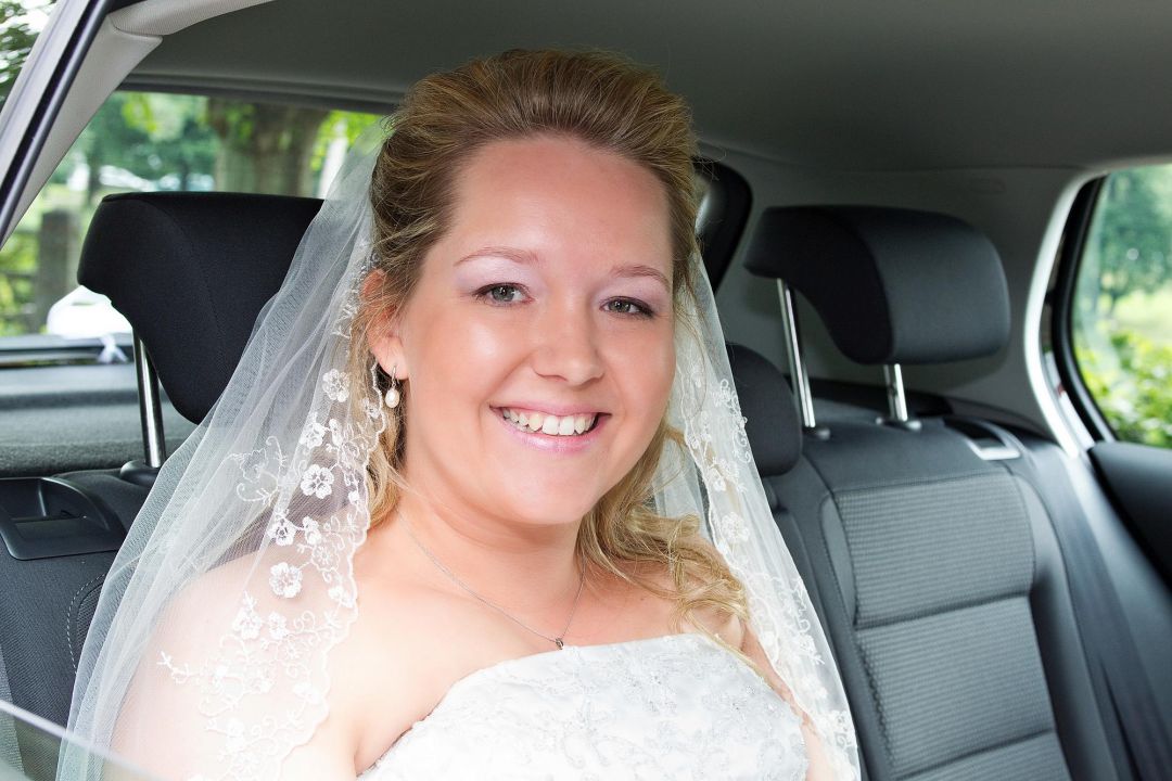 Junge Braut im Auto lächelt in die Kamera. Hochzeit Fotograf Hamburg Peter Vogel