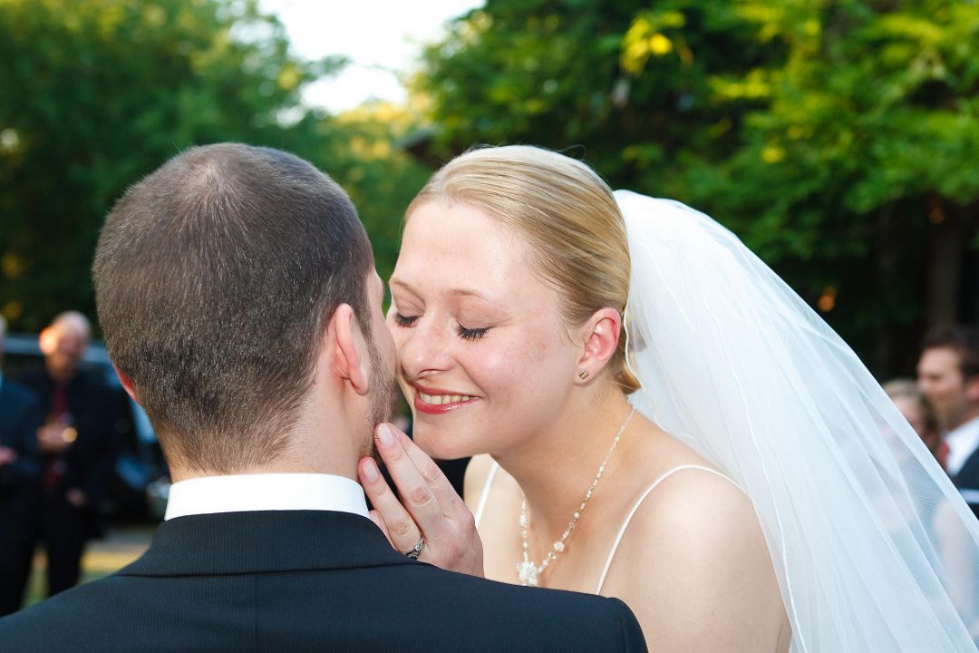 Junge Braut im weißen Brautkleid mit Schleier küßt Bräutigam. Hochzeitsfoto von Peter Vogel