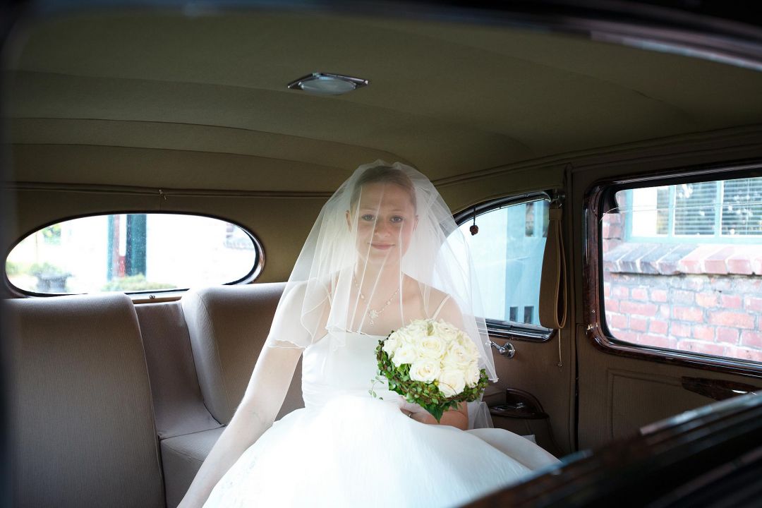 Junge Braut mit Schleier im historischen Auto auf dem Weg zur Trauung, Hochzeitsfotos von Peter Vogel, Hamburg